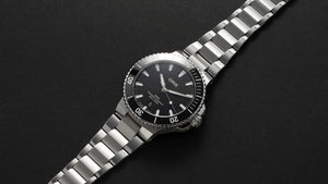 Silver Oris watch with black dial on a dark background