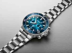 Silver Oris watch with blue face on a gray background