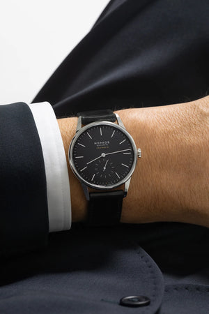 man wearing a suit with a black watch on a white background