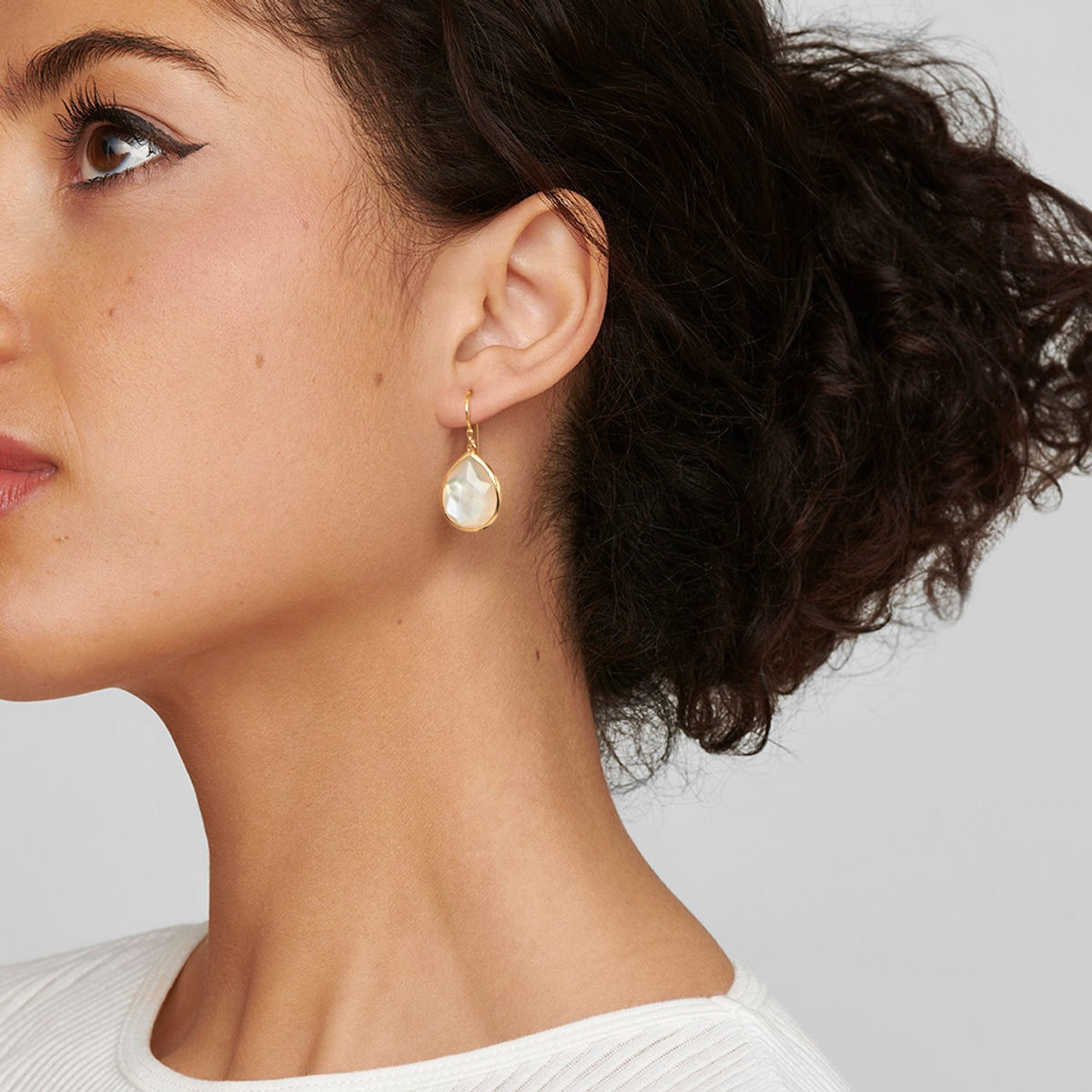 Close-up side view of 18K Gold Medium Mother-of-Pearl Teardrop Earrings showcasing rock crystal on a model