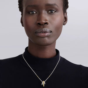 model wearing a black shirt and a silver chain necklace that features 3 hanging rings in silver, gold and diamonds on a white background