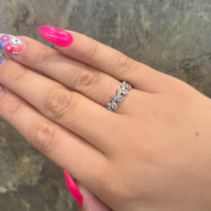 Hand wearing a diamond eternity band on the ring finger; bright pink nails with flower nail art visible.