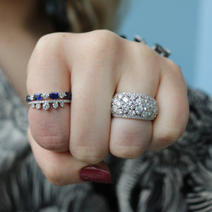 Front view of 0.43ctw diamond fashion ring showing pavé diamond dome on model's middle finger against blurred blue background
