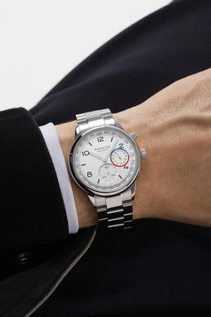 Gentleman wearing a silver watch with white dial and blue and red markings on a white background