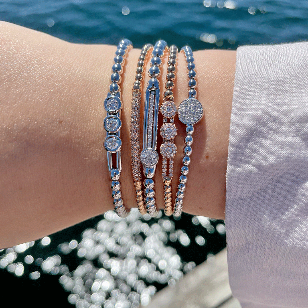 Wrist view of 0.60ctw, 18K White Gold Tresore Stretch Bracelet stacked with others, diamond cluster detail, sunlit water