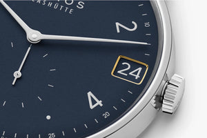Watch face with blue background, white hands, and gold number '24'.