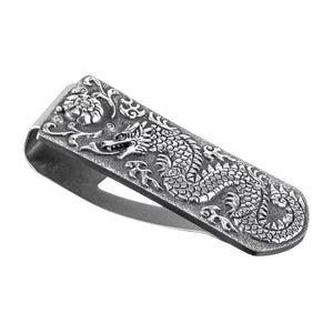 Angled view of William Henry Zurich Naga sterling silver money clip with hand-carved dragon and floral detail on white