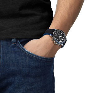 Person wearing a black watch with a blue strap on a plain background