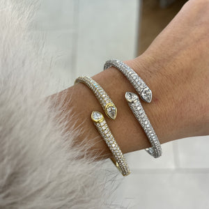 snake-head cuff bracelets with pavé-set stones worn on a wrist. Two bracelets are silver-toned and one is gold-toned, with clear stones forming the body and pear-shaped stones at the head.