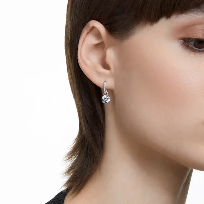 Close-up of Constella Drop Earrings showing white pavé-set hoops and dangling clear zirconia, rhodium plated, 3/4-inch drop on model