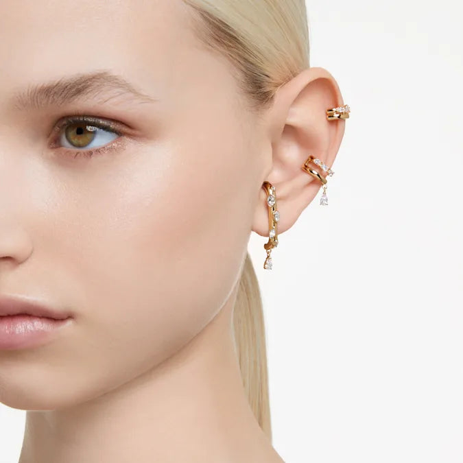 Side view of Dextera ear cuff set of three, gold plated with clear crystals, worn on model’s ear against white background