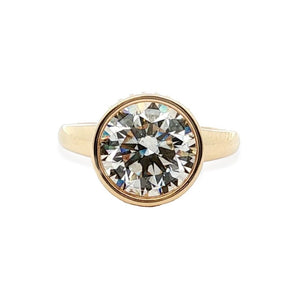 Front view of 18K yellow gold engagement ring showcasing 4.01 ct round bezel-set center diamond on white background