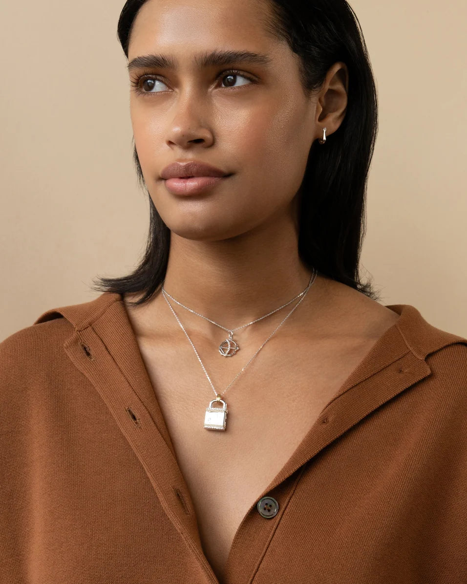 a woman wearing a brown sweater silver necklaces on a beige background
