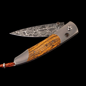 Folding pocket knife with Damascus-pattern blade, zebrawood handle and braided leather lanyard, "wh" logo on blade