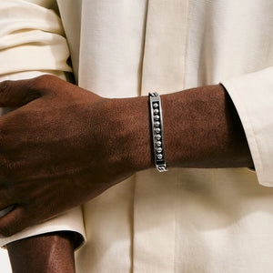 Silver bracelet on a wrist with a neutral background
