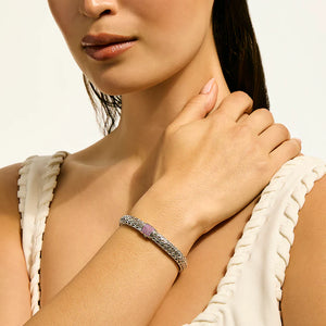 Close-up of a woman wearing a bracelet on a neutral background