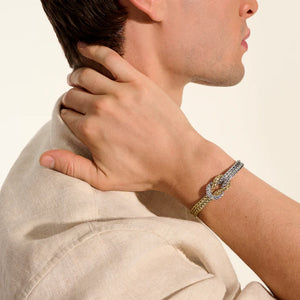 Person wearing a gold and silver bracelet on a beige background