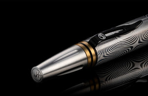Close-up of William Henry Caribe 16 pen showing Damascus steel barrel and brass spacer rings on black background