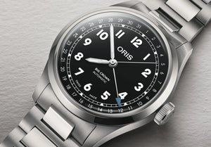 Oris watch with black dial and silver metal strap on a gray background