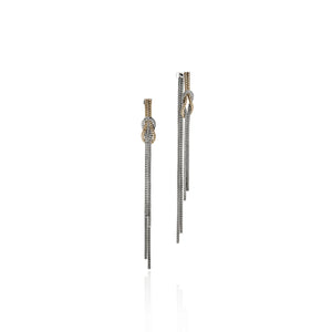 Silver and gold drop earrings tied in a knot on a white background