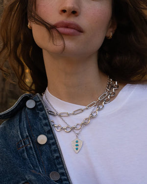close up of a woman wearing a white t-shirt and denim jacket along with silver necklaces