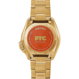 Gold tone Seiko watch with orange case back with FTC, 40th anniversary centered on the back on a white background