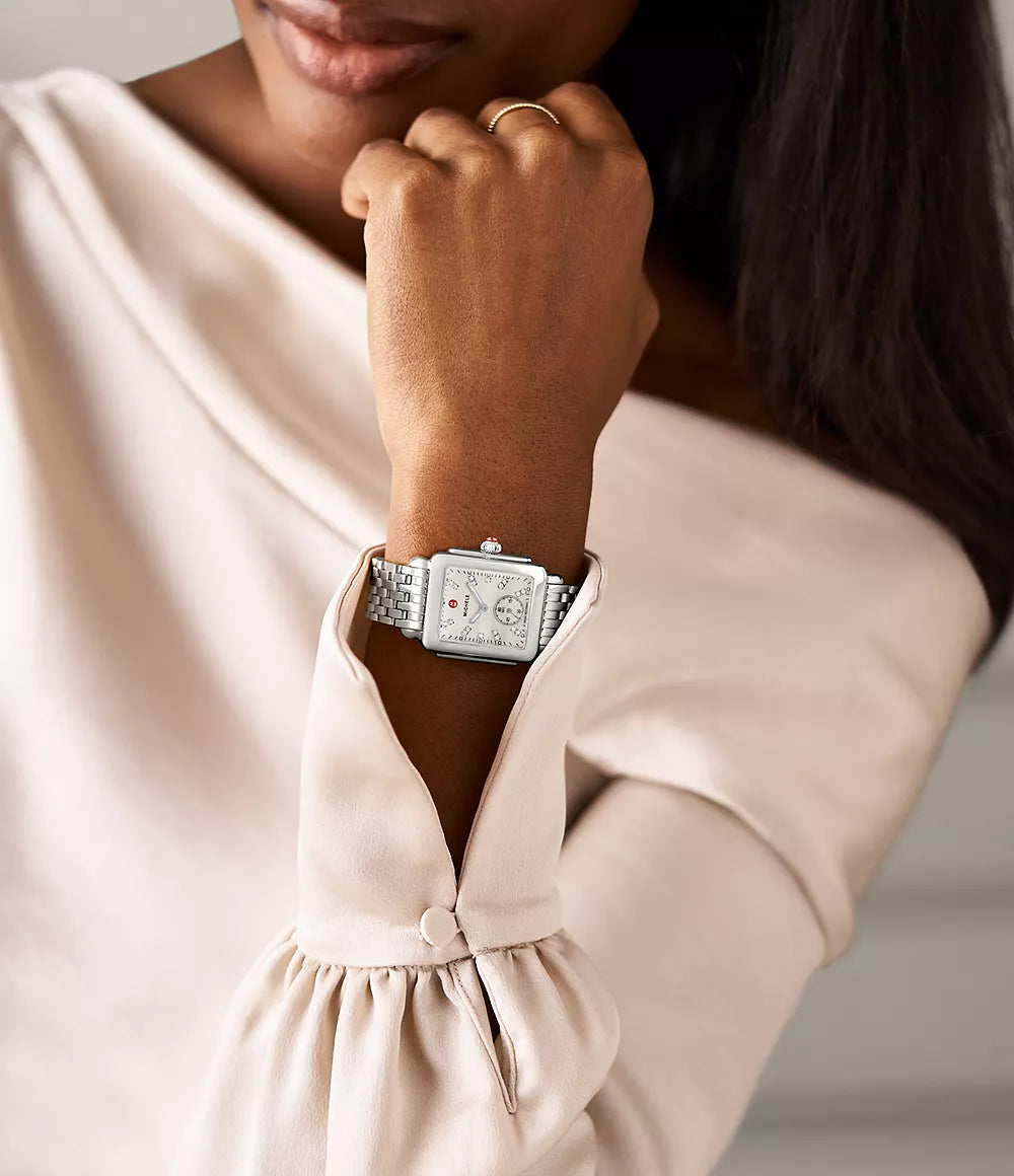 Wrist view of Deco Mid stainless steel watch with rectangular diamond-accent mother-of-pearl dial on model in cream blouse
