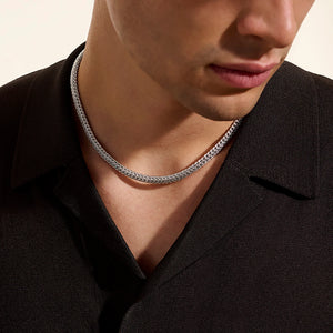 Person wearing a silver chain necklace against a neutral background