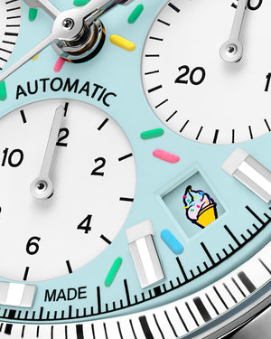 Close-up of Freedom Chrono Enjoy Life Sprinkles watch face showing pastel blue dial, colorful sprinkle hour markers, three subdials, 'AUTOMATIC' text and ice cream icon