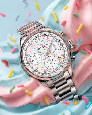 Angled close-up of Norqain Freedom Chrono Sprinkles watch with pink sprinkle dial, chronograph subdials and steel bracelet