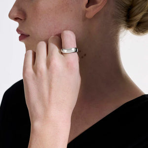 Close-up of a person wearing a silver ring on a plain background