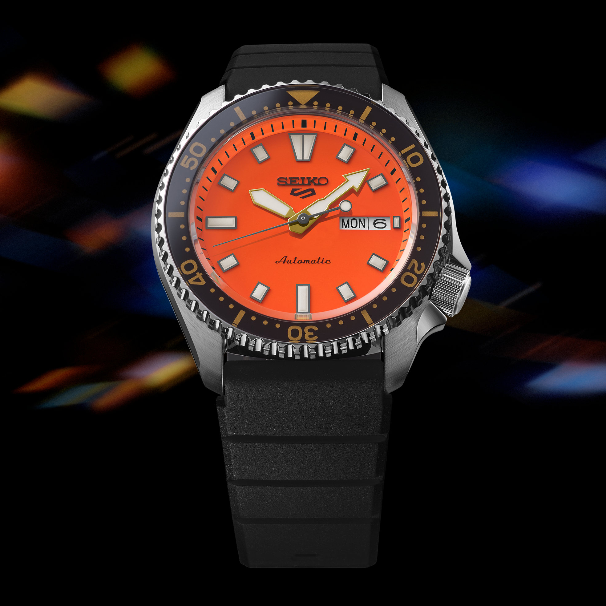 Front view of Seiko SRPL89 watch with bright orange dial, day-date at 3 o’clock, black rotating bezel and black rubber strap