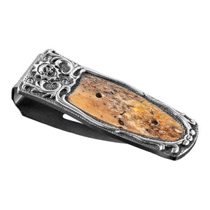 Angled view of William Henry Boneyard money clip with sterling silver carving and fossil mammoth inlay on white background
