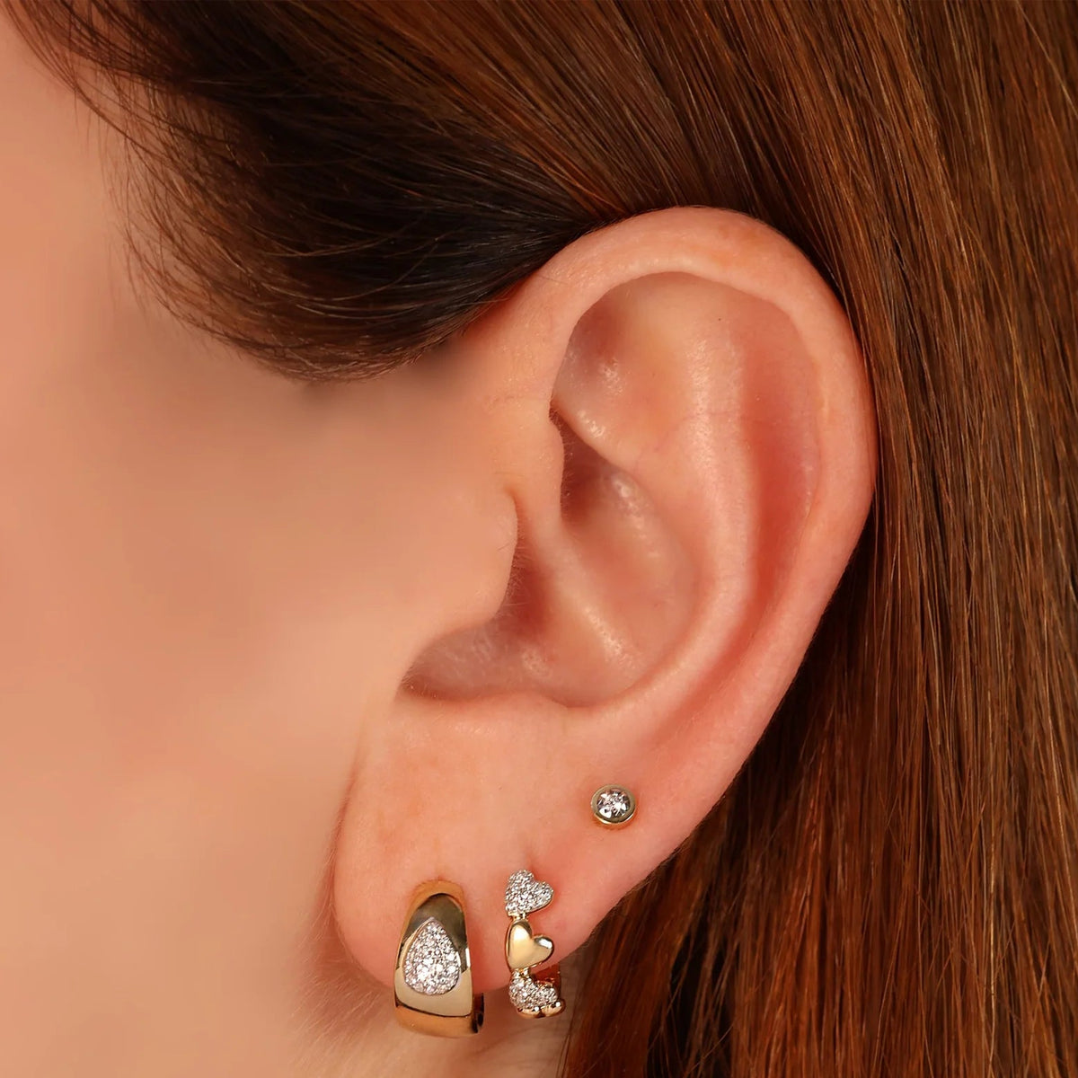 Close-up of 0.04ctw diamond bezel stud earring in 14K yellow gold on a model’s ear, showcasing its bezel-set diamond