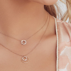 Two-layer rose-gold necklace set with two circle pendants worn on a woman's neck and collarbone.