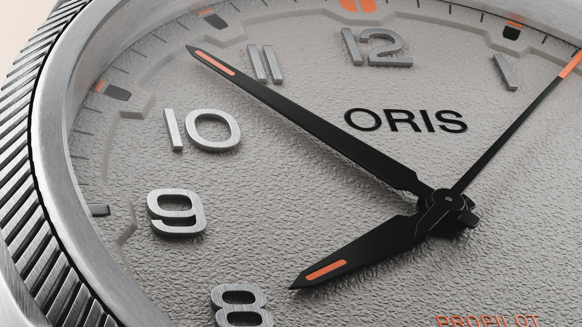 Closeup of ORIS ProPilot Date 41mm grey-dial watch showing textured dial, silver numerals and black hands with orange accents