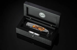 Black leather-bound knife set with a pocket knife and sheath in an open box on a black background.