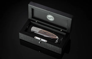folding knife sitting in a dark wooden box