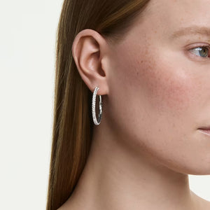 model wearing silver tone crystal hoops on a white background