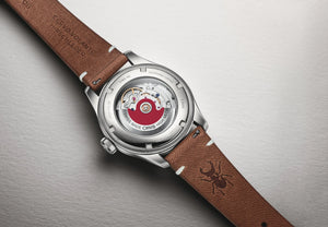 Watch with brown leather strap and visible brand name on a gray background