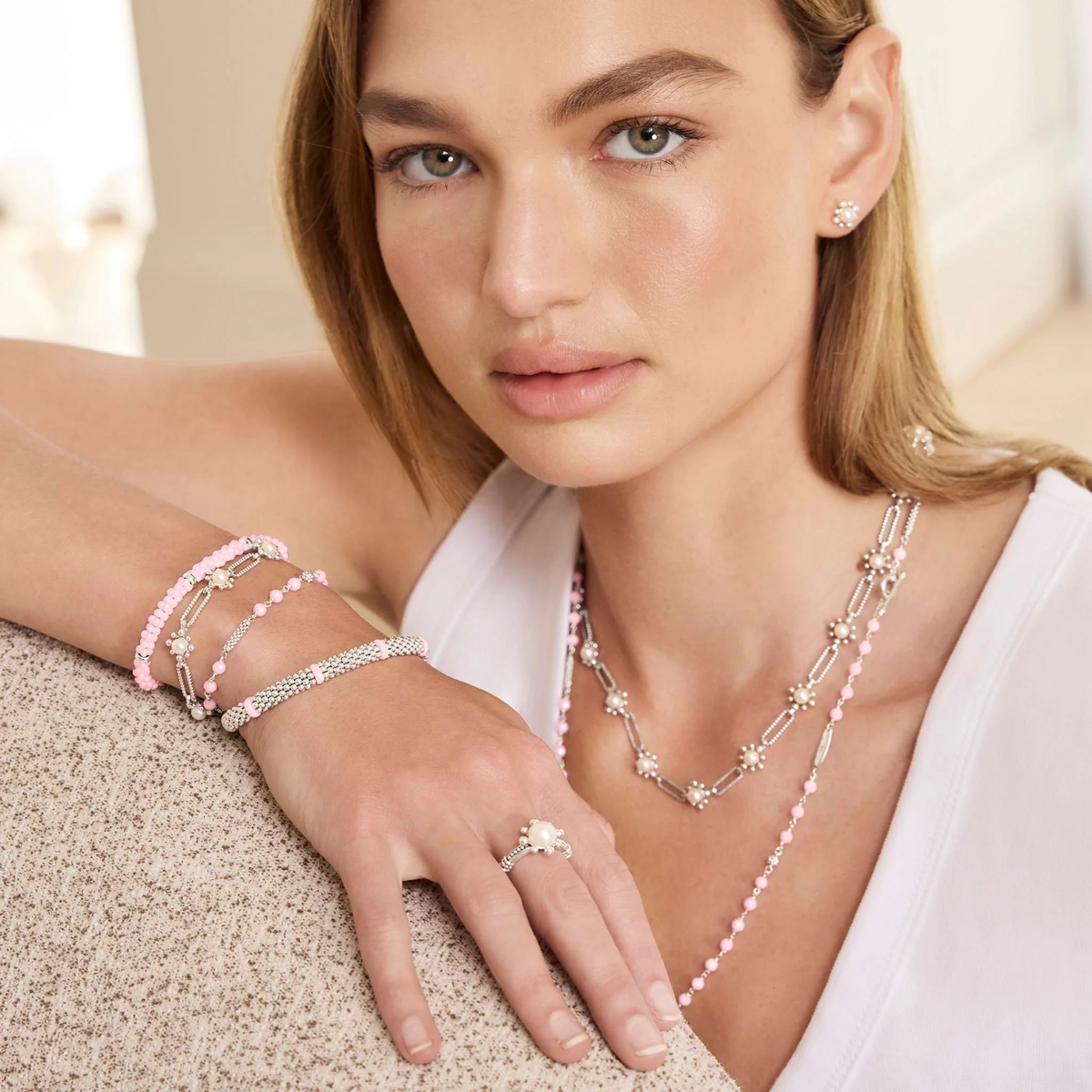 Close-up of model wearing pink ceramic bracelet with five silver station beads, 5mm, on wrist over white sleeveless top
