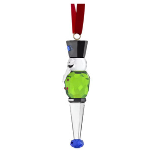 side view of a green nutcracker ornament with red ribbon on a white background