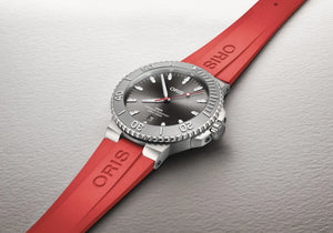 Oris watch with red strap on a gray background