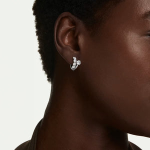model is wearing silver tone zirconia hoop earrings on a white background