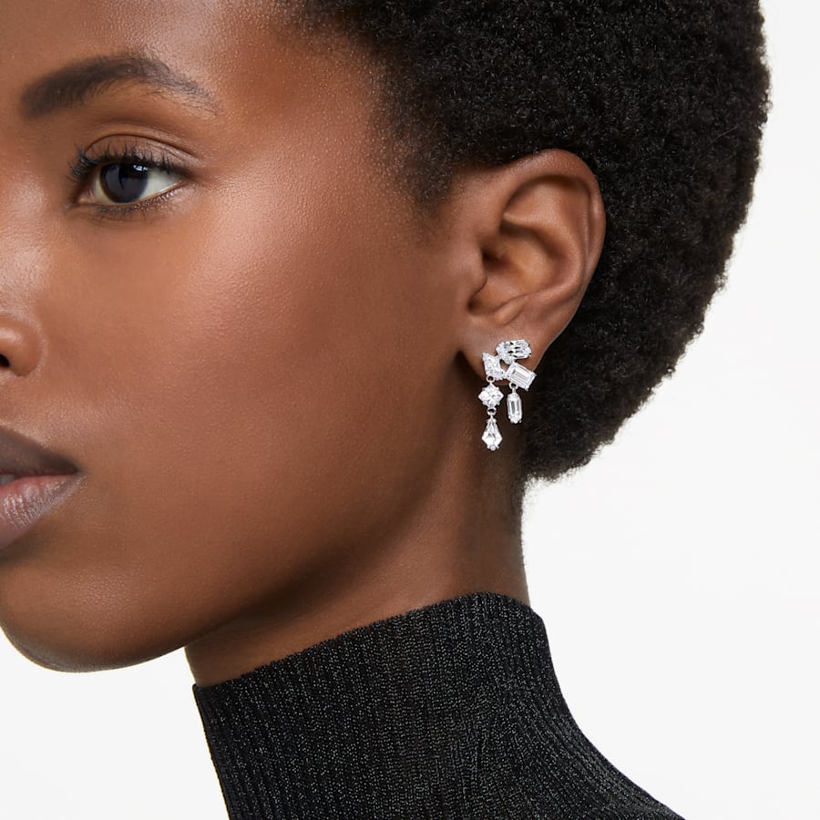 Close-up side profile of model wearing Mesmera drop earrings, rhodium-plated with mixed-cut white crystals on white backdrop