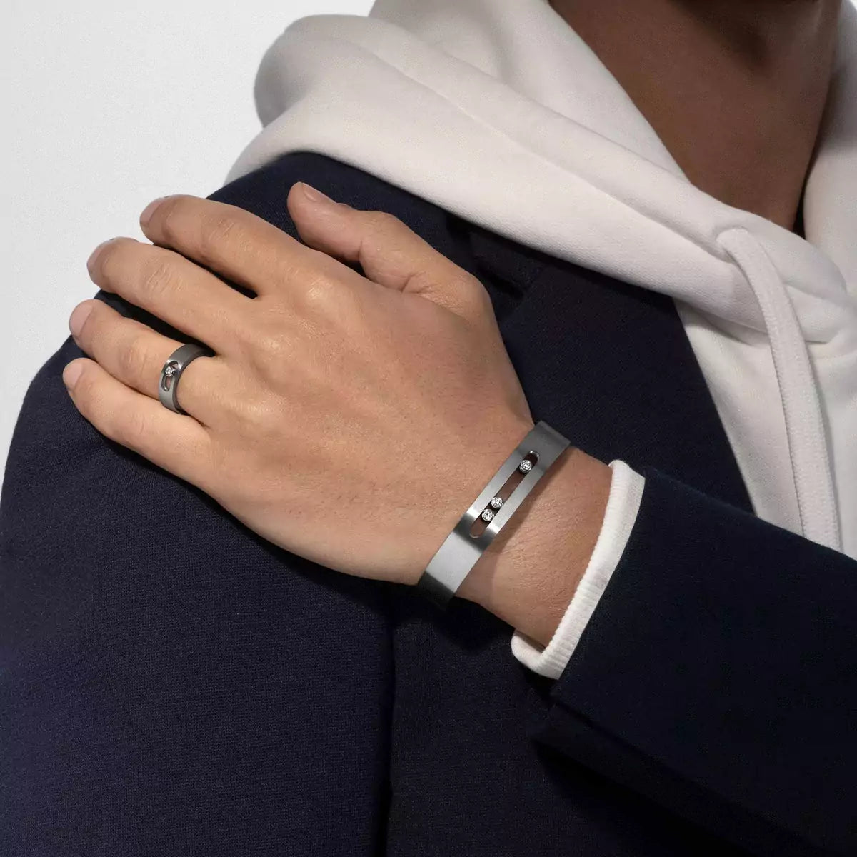 Hand wearing a silver bracelet with a ring on a white background