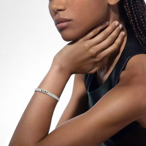 Woman wearing a silver bracelet on her wrist with a plain background