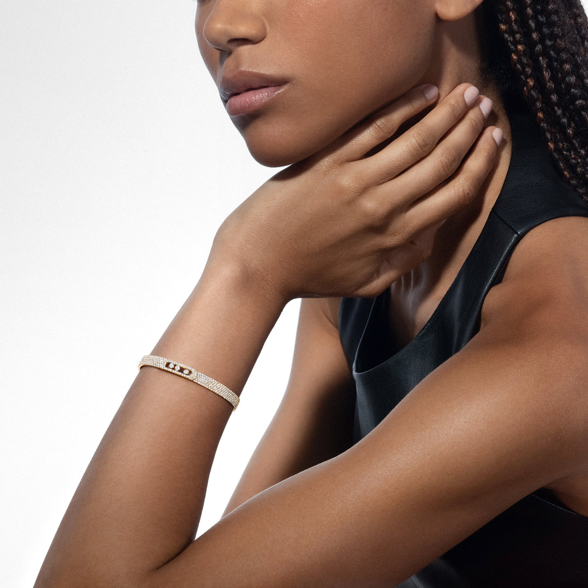 Wrist view of 2.35ctw yellow gold diamond bangle showing three moving diamonds against gray background