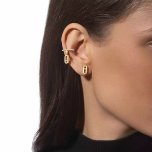 Close-up of a person wearing gold hoop earrings with a plain background