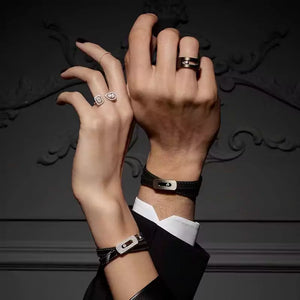 Close-up of hands wearing rings and a bracelet against a dark background